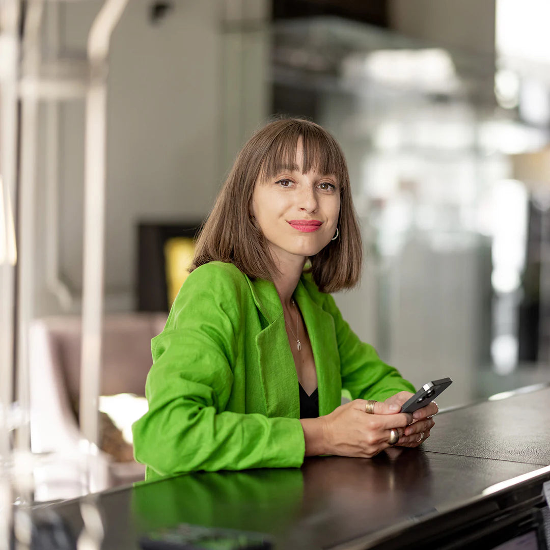 Architecture studio manager in a green jacket holding a phone in an indoor setting