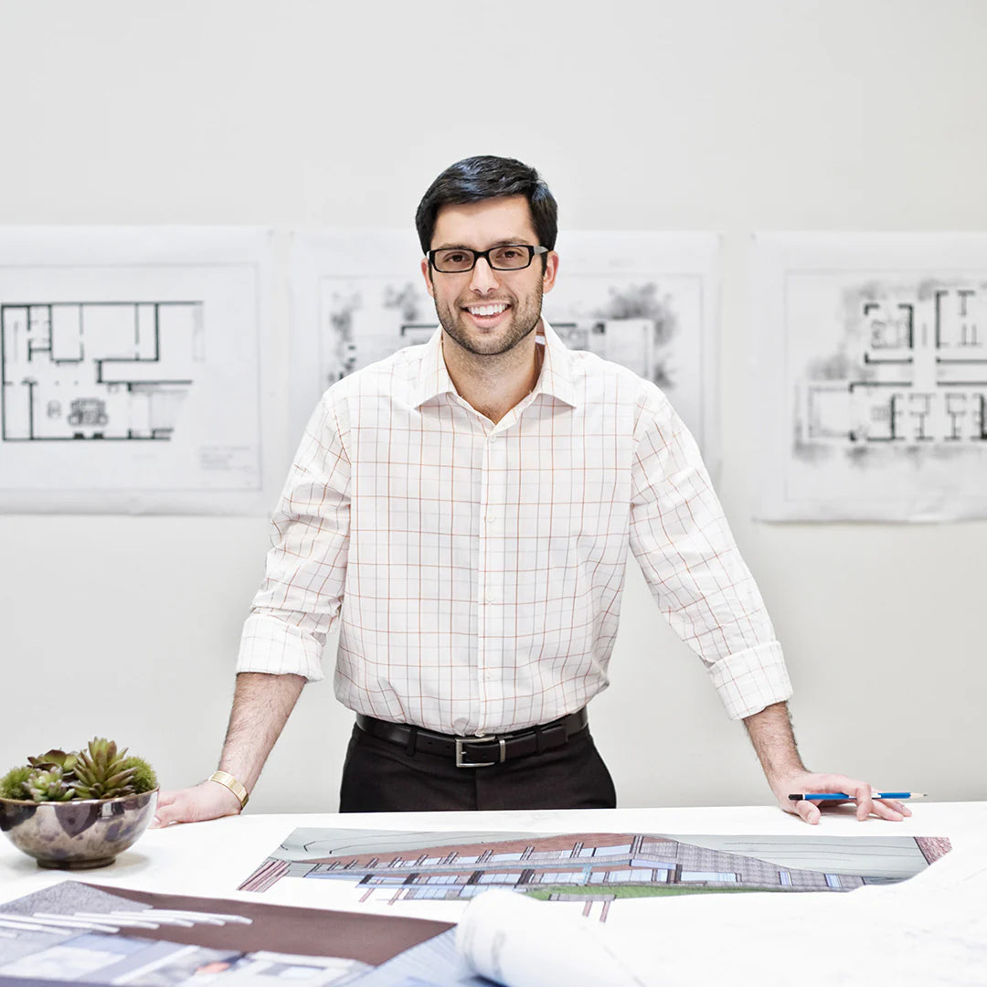 architect standing behind a desk with architectural blueprints in an office setting